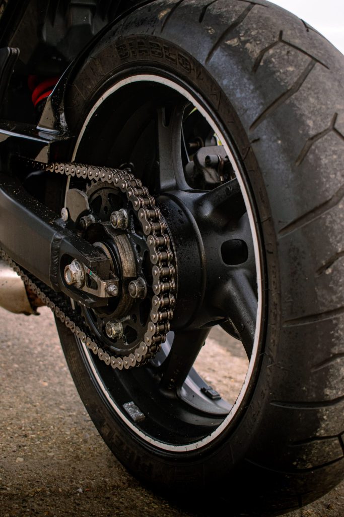 Close-up view of a motorcycle's rear wheel and chain showcasing mechanical details.