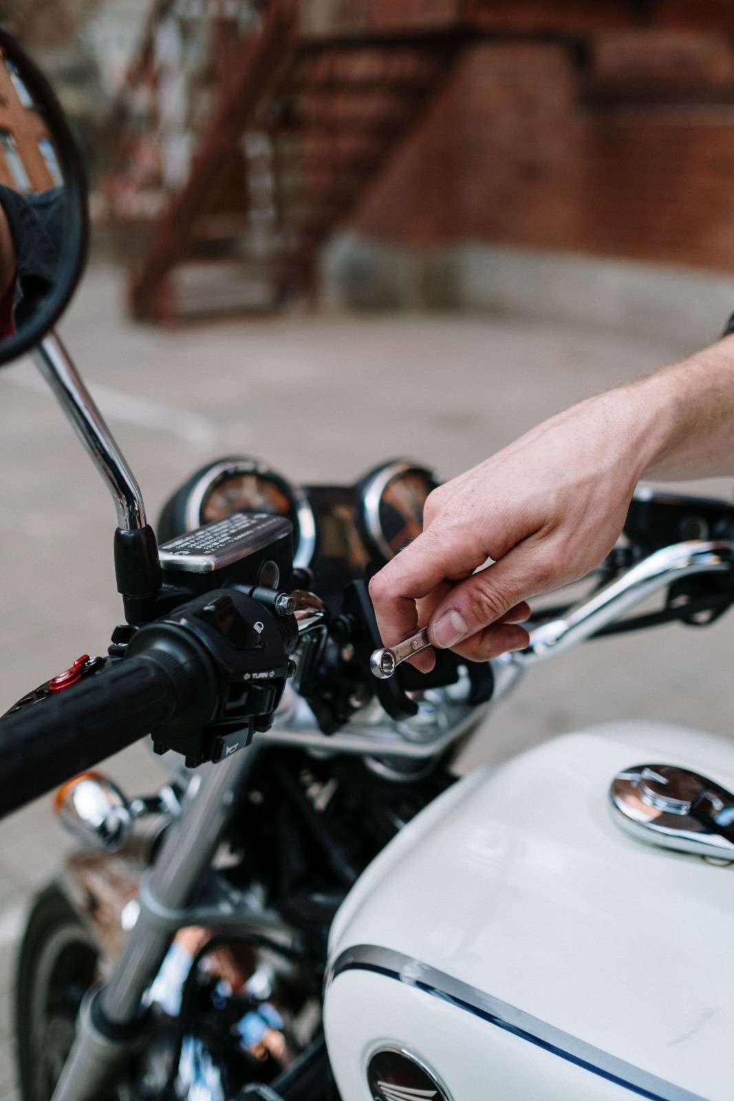 Hand hält Werkzeug an Motorrad